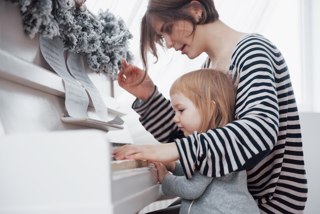 Mère et fille jouant du piano blanc, bouchent wiew