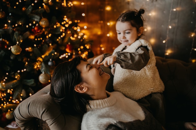 Mère et fille jouant la veille de Noël à la maison, assise sur un canapé