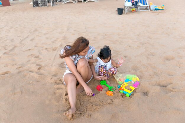 Mère et fille jouent au sable sur la plage latérale de la mer au coucher du soleilThailaneMoment de détente