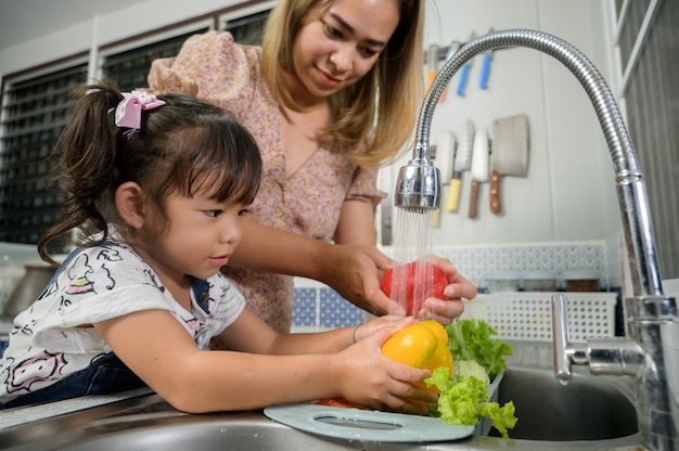 Mère et fille lavent les légumes dans la cuisine