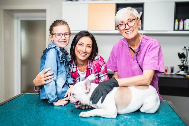 Mère et fille avec leur bouledogue français chez vétérinaire.