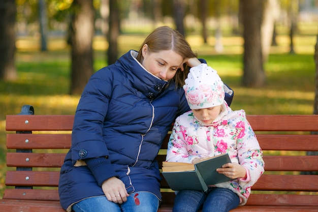 Mère et fille lisent un livre et s'amusent dans la nature