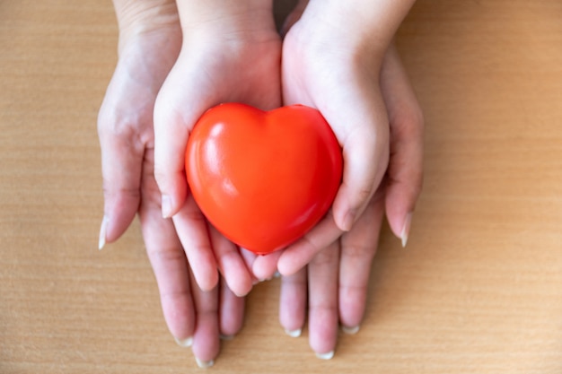 Mère et fille mains tenant coeur rouge, soins de santé, don et concept d'assurance familiale