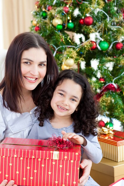 Mère et fille à la maison tenant un cadeau de Noël