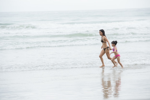 Mère et fille marchant sur la plage.