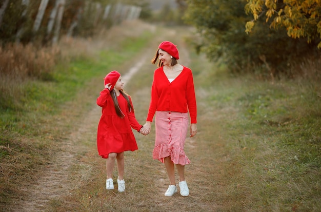 Mère et fille marchent ensemble dans un verger de pommiers vêtements rouge vif