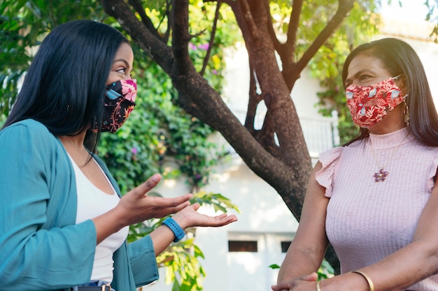 Mère et fille avec masque de protection parlant dans le parc