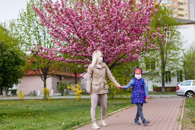 Mère et fille avec des masques marchant et parlant dans la rue