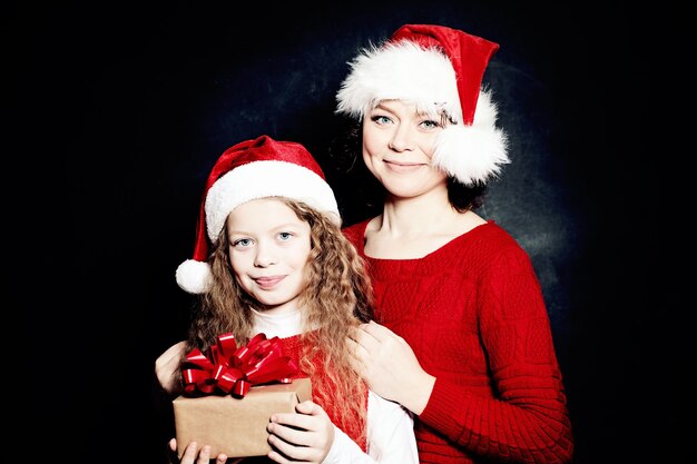 Mère et fille de Noël en bonnet de noel s'amusant avec un cadeau famille heureuse en pull d'hiver rouge