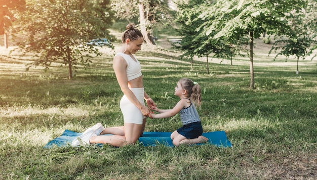 Mère et fille ont un cours de yoga dans le parc