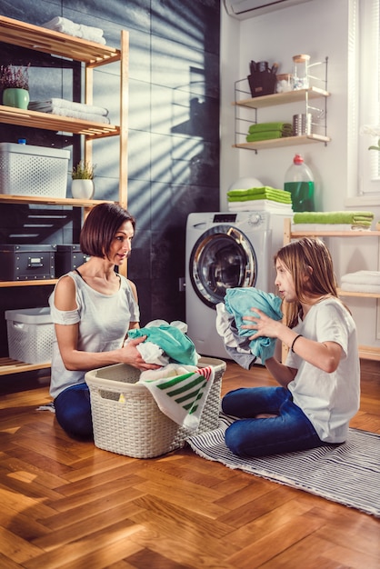 Mère et fille parlant et triant le linge sur le sol