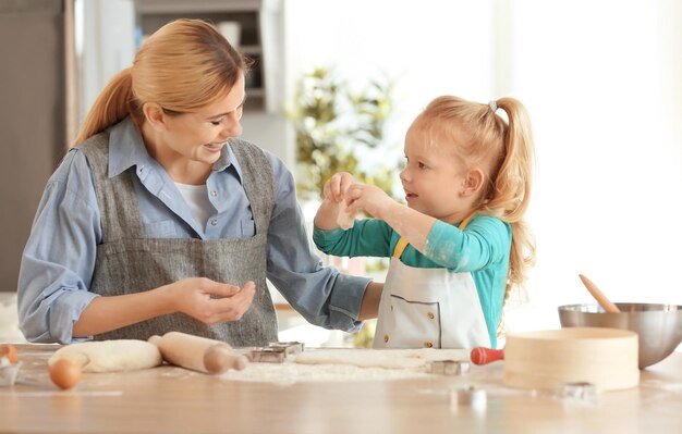 Mère et fille avec de la pâte à table à l'intérieur