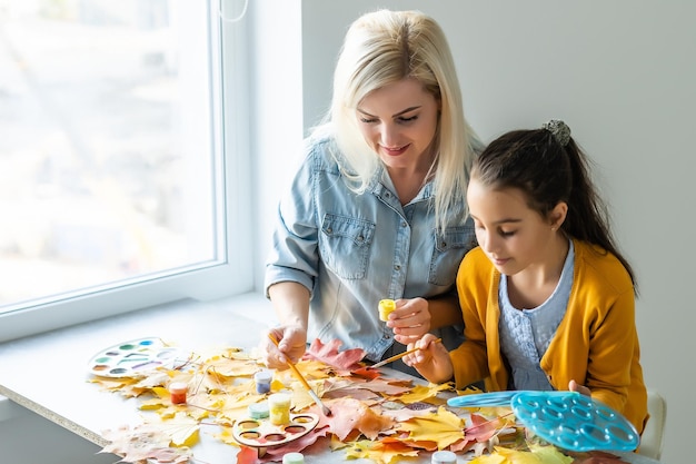 mère et fille peignent les feuilles d'automne