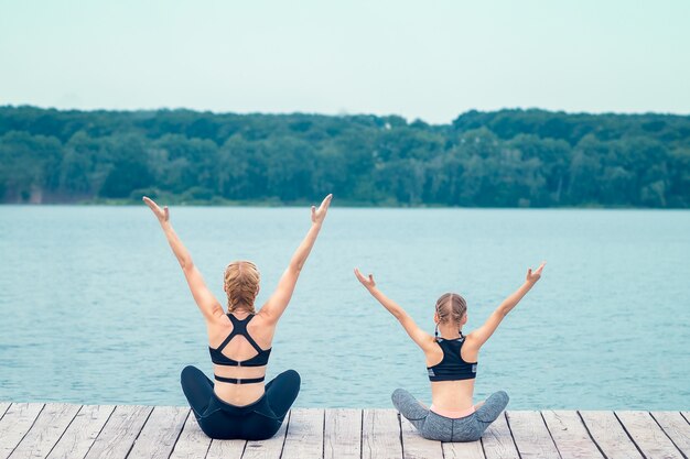 Mère et fille pratiquant le yoga sur une jetée