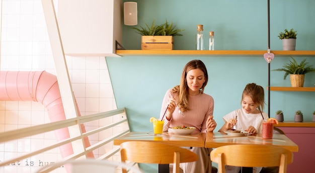 Mère et fille prenant un petit déjeuner avec des jus de fruits frais au café