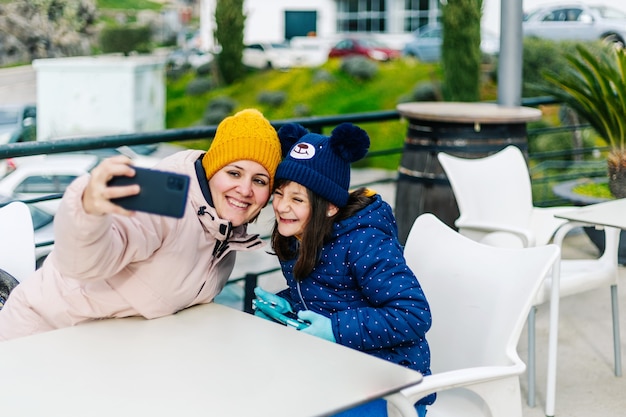 Mère et fille prenant un selfie sur une terrasse extérieure