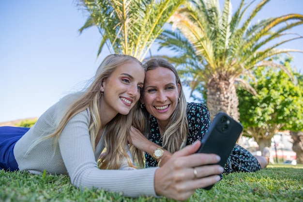 Mère et fille prennent un selfie allongées ensemble dans un pré