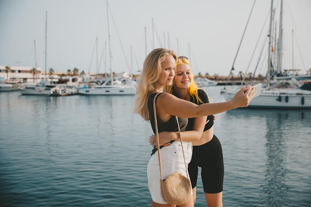 Mère et fille prennent des selfies sur fond de mer et de yachts