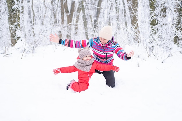 Mère et fille en promenade d'hiver dans la nature. femme et enfant fille font bonhomme de neige