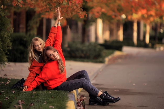 Mère et fille en pulls orange s'amusent lors d'une promenade dans la rue près des maisons de campagne