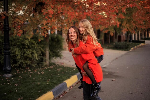 Mère et fille en pulls orange s'amusent lors d'une promenade dans la rue près des maisons de campagne