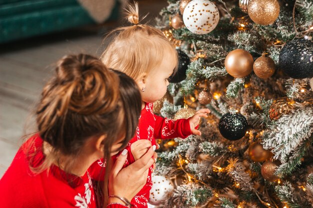Mère et fille regardant des jouets sur l'arbre le soir de Noël