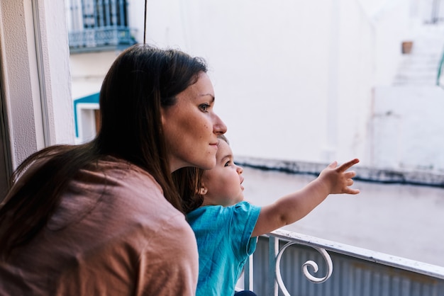 Mère et fille regardant par la fenêtre de la maison