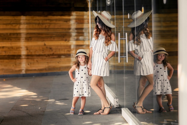 Mère avec fille en robe et chapeaux sur la terrasse