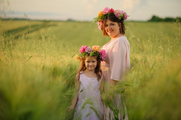 Mère et fille en robes roses dans un champ de blé vert