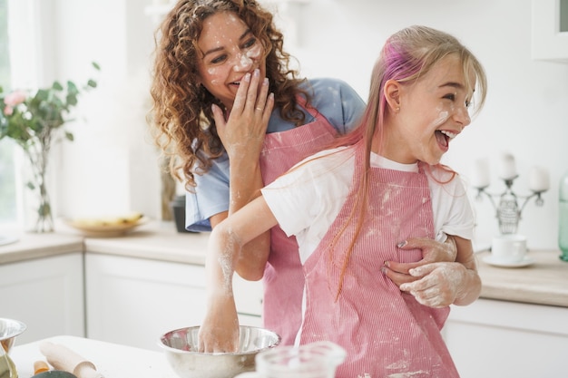 Mère et fille s'amusant pendant la cuisson de la pâte dans la cuisine