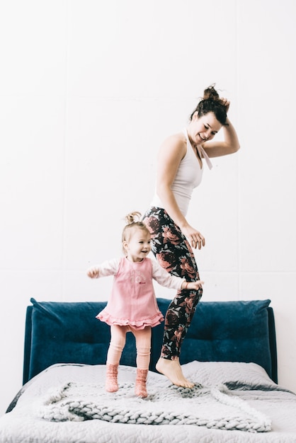 Mère et fille sautant sur le lit. Bonne fête des mères!