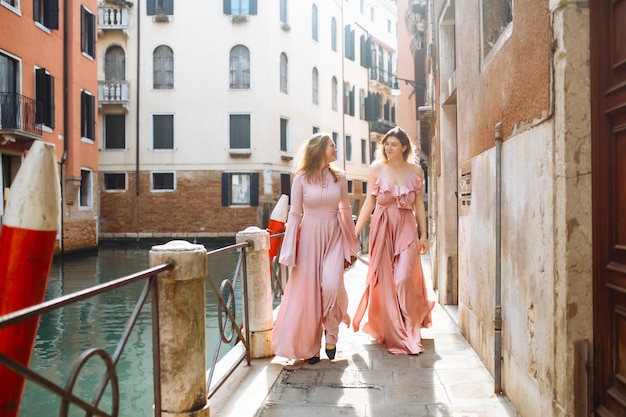 Mère et fille se promènent sous le soleil de Venise en robes roses douces Concept de mode de vie actif