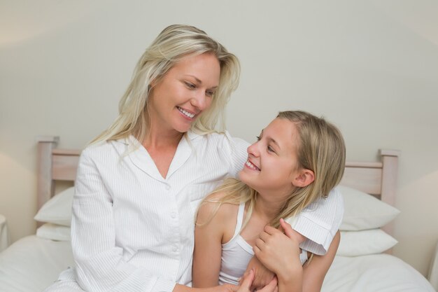 Mère et fille se regardant au lit