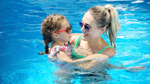 Mère et fille se reposant et nageant dans une piscine en été