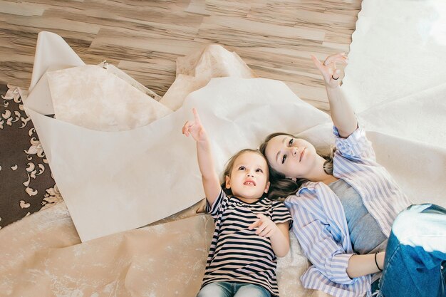 Mère et fille se trouvent au milieu de la pièce sur un vieux papier peint et planifient un nouvel intérieur