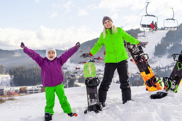 Mère et fille avec des snowboards jouent dans la neige