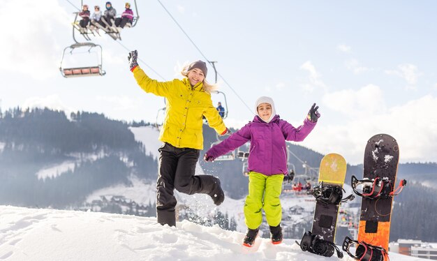 Photo mère et fille avec des snowboards à la station d'hiver