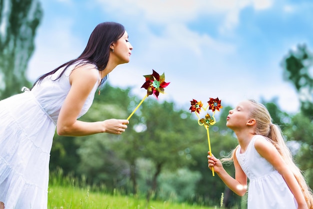 Mère et fille soufflant sur un jouet en plein air