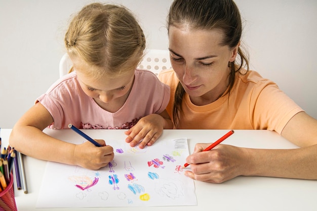 Mère et fille souriantes dessinant avec des crayons de couleur sur papier Vue de dessus mise à plat