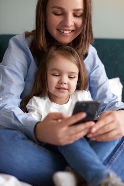 Mère et fille souriantes jouant à un jeu sur smartphone