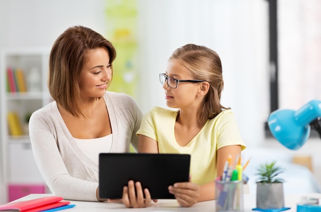 mère et fille avec une tablette faisant leurs devoirs