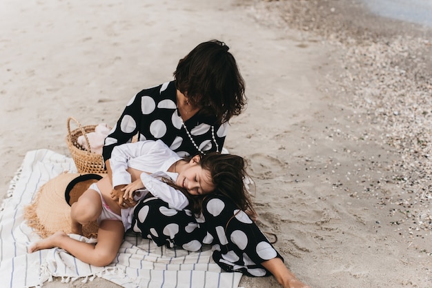 Mère et fille tenant par la main et marchant sur la plage