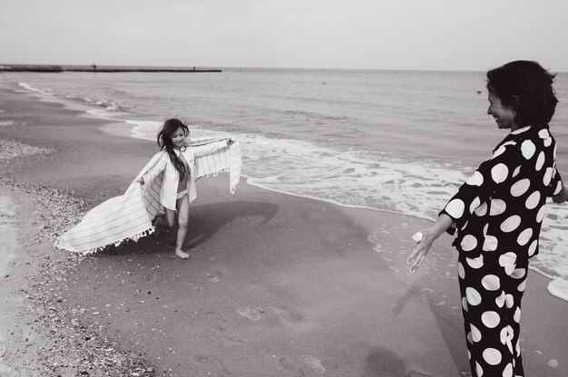 Mère et fille tenant par la main et marchant sur la plage