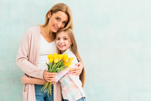 Mère et fille avec des tulipes étreignant et souriant