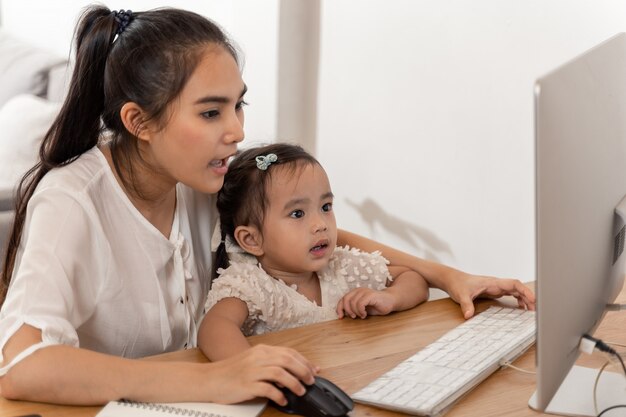 Mère et fille utilisant un ordinateur et Internet pendant que la mère travaille à domicile