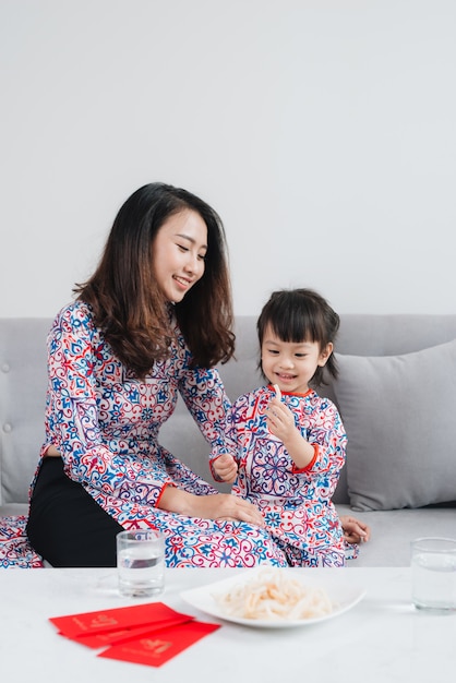 Mère et fille vietnamiennes en costume traditionnel Ao Dai, célèbrent le nouvel an à la maison. Vacances du Têt.