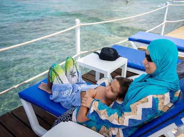 Mère et fils arabes assis et profitant de la jetée de la plage