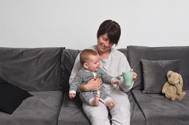 Mère et fils assis sur le canapé, la mère tient une tasse