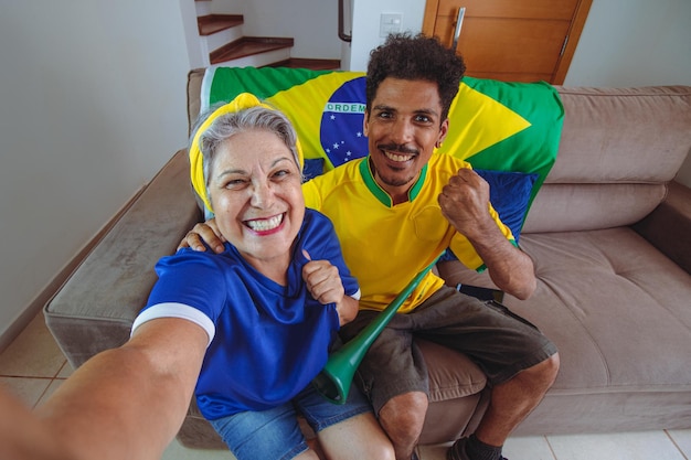 Mère et fils célébrant la coupe dans le salon en regardant la télévision acclamant le Brésil