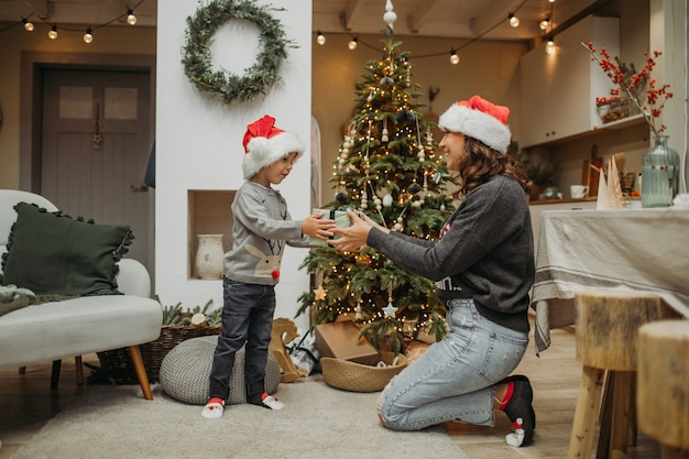 Mère et fils en chapeaux de père Noël s'amuser et se détendre à la maison. Concept de Noël.